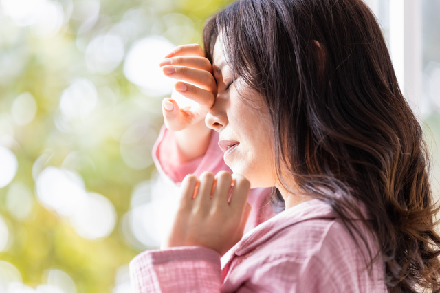 朝の光を浴びる部屋着を着た体調不調の女性